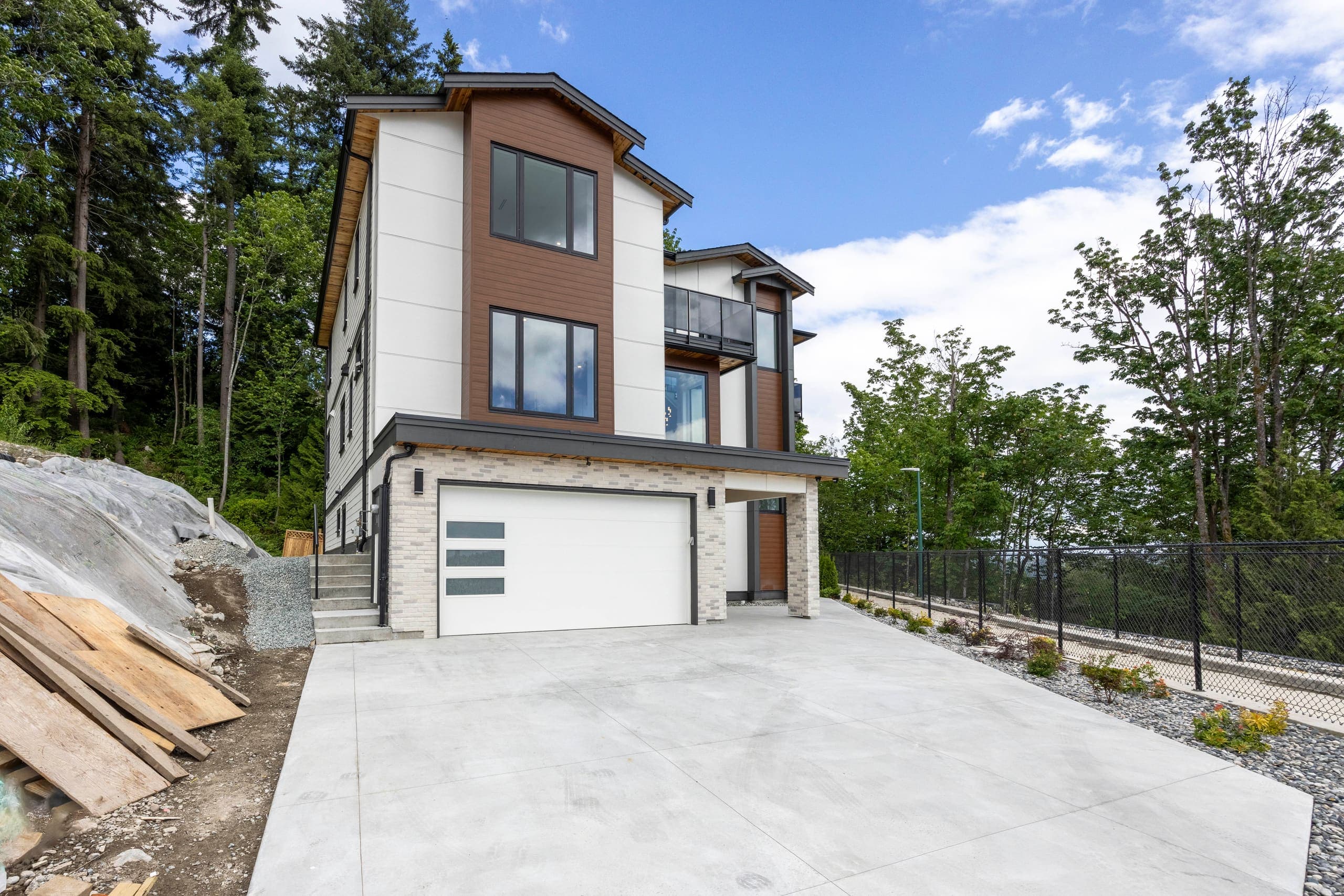 Front elevation from the driveway, three storeys stepping down the slope — The Monashee House